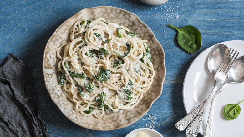 A bowl of pasta with spinach and cream sauce