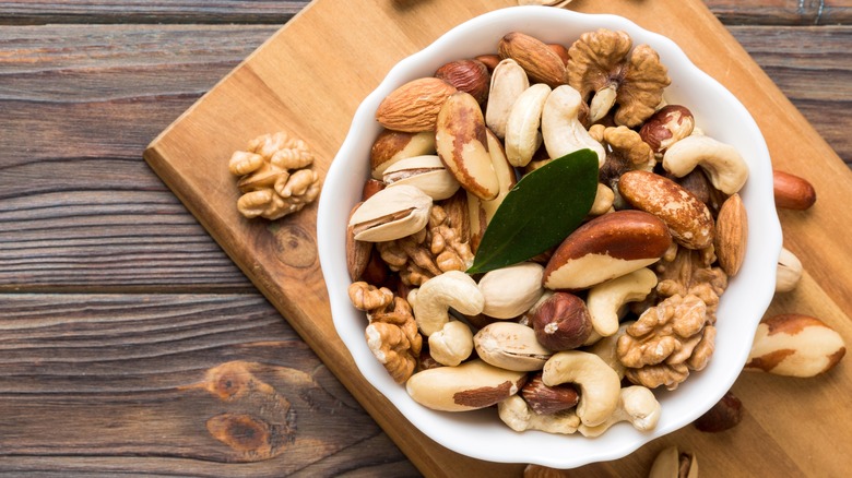 A bowl of mixed nuts on a cutting board