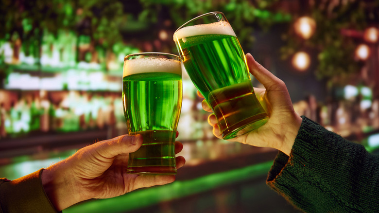 Two people clinking glasses of green beer.