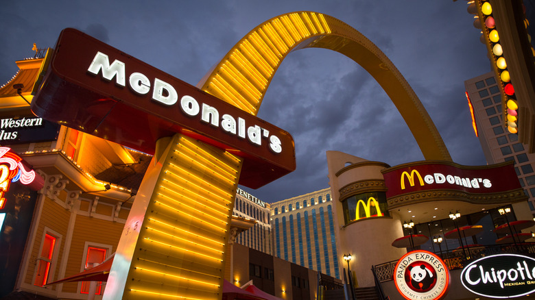 A large neon golden arch with the McDonald's logo crosses over a building