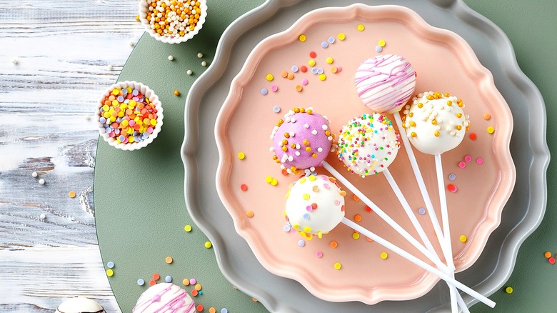 Vanilla cake pops with sprinkles on grey and pink scalloped plates