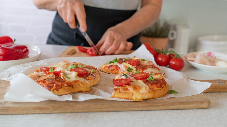 person putting toppings on a frozen pizza