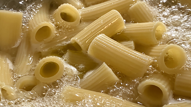 A closeup shows pasta noodles in boiling water.