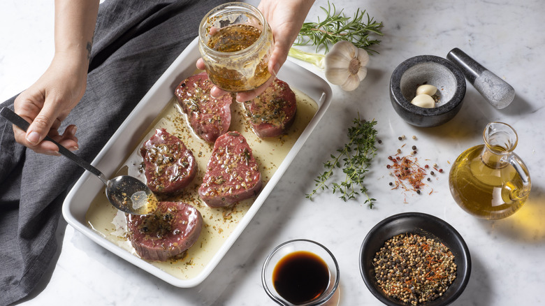 Person spooning marinade onto raw meat