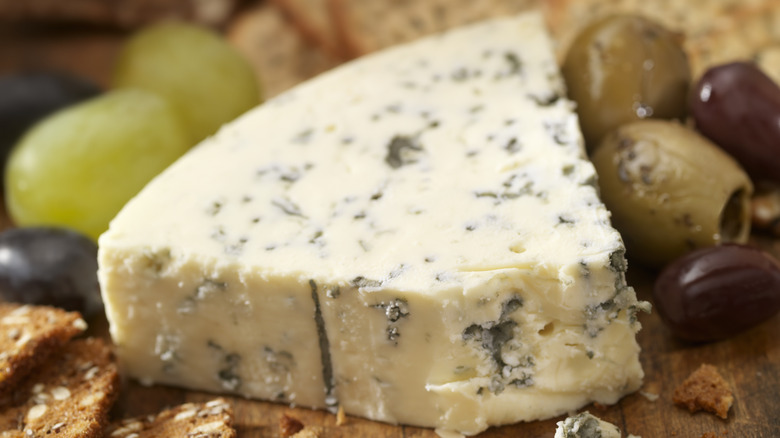 blue cheese surrounded by crackers and olives