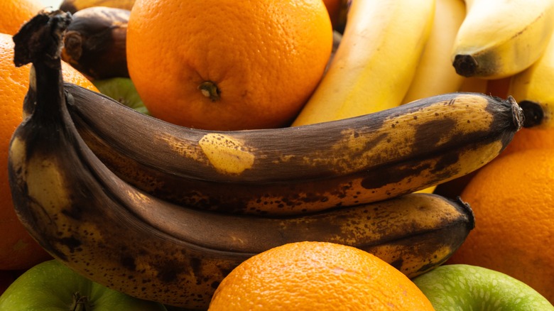 Brown bananas in middle of oranges and apples