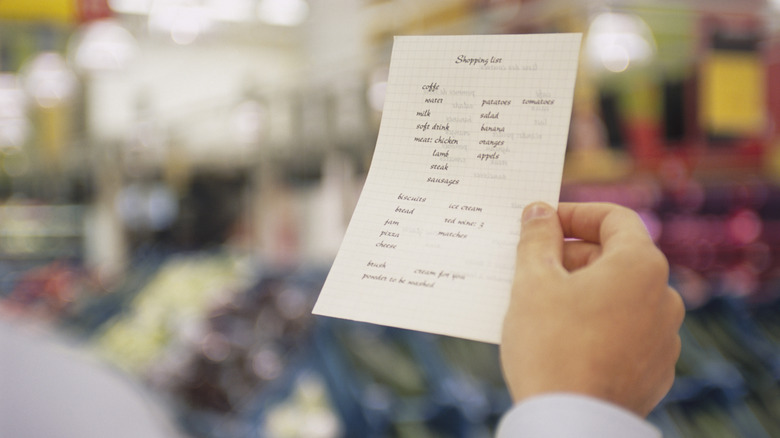 A person holding a shopping list in a grocery store