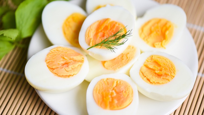 Sliced hard-boiled eggs sit on a plate garnished with dill