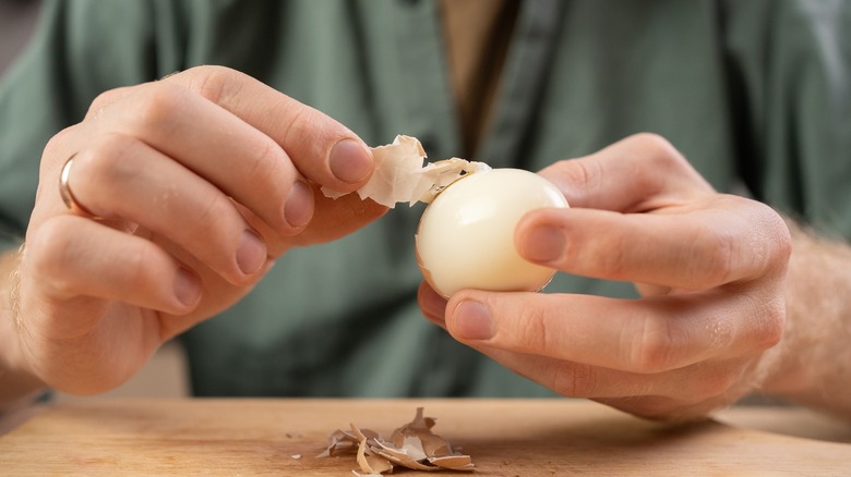 A man peels a hard-boiled egg