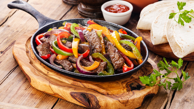 Beef fajitas in skillet with tortillas