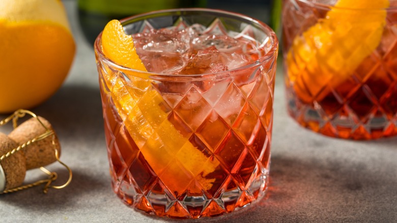 a glass of a negroni sbagliato cocktail garnished with orange peel