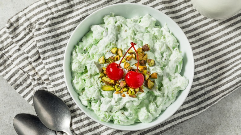 Pistachio fluff in a bowl with cherries and pistachios on top