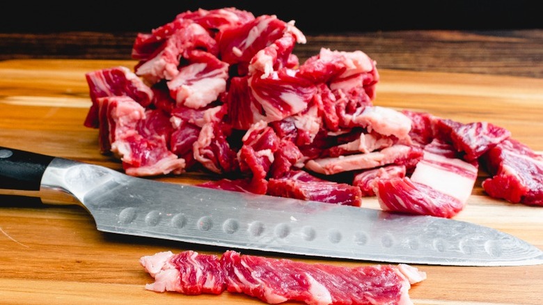 Thinly sliced beef with a knife on a cutting board