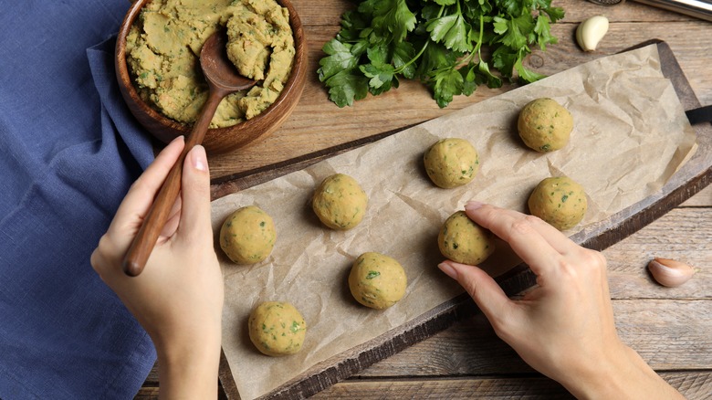 Woman making falafel balls from dough mix