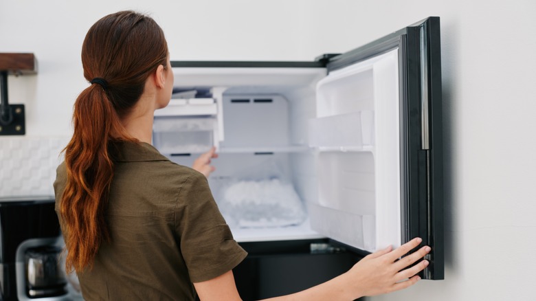 woman opening freezer of ice cubes