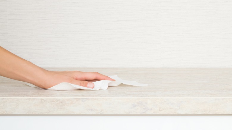 A hand wiping down a counter with a cloth