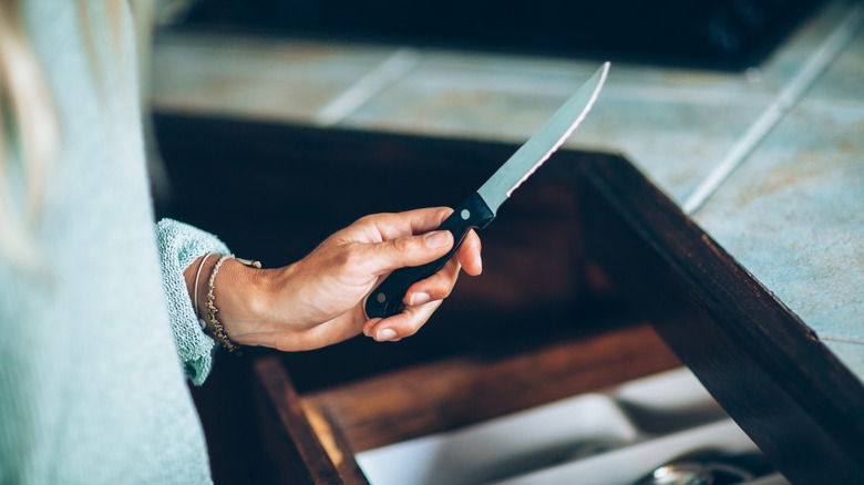 woman pulling a knife out of a drawer