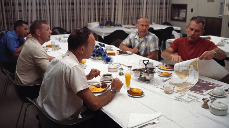 Apollo 11 astronauts and scientists eating a meal before launch