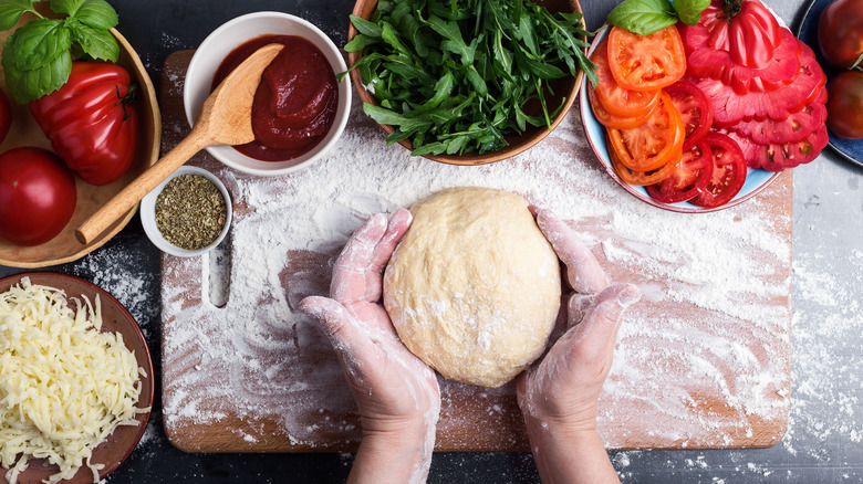 Hands making pizza dough with ingedients