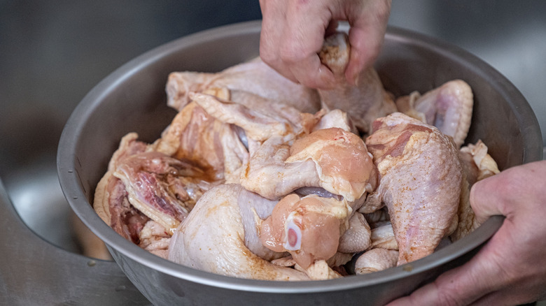 Hands prepping a bowl of chicken cuts