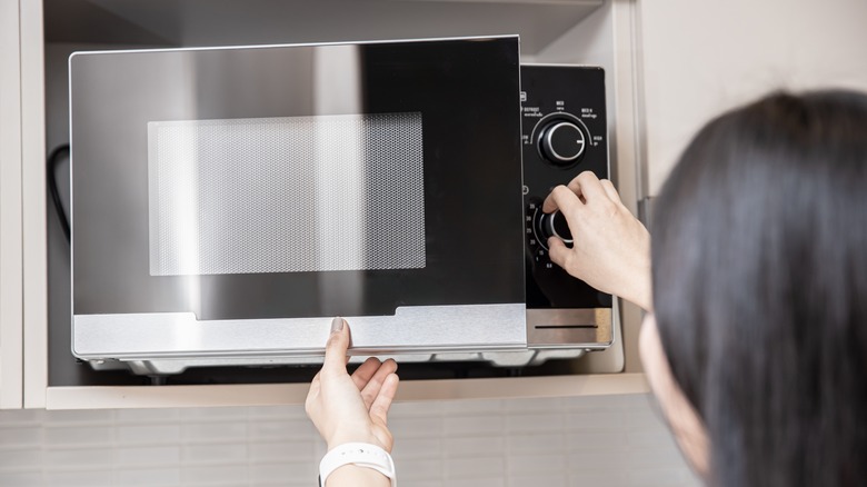 Woman adjusting microwave time