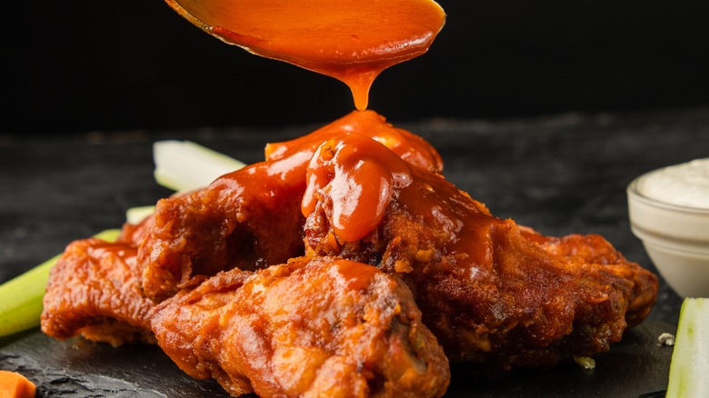 Buffalo sauce being drizzled onto wings.