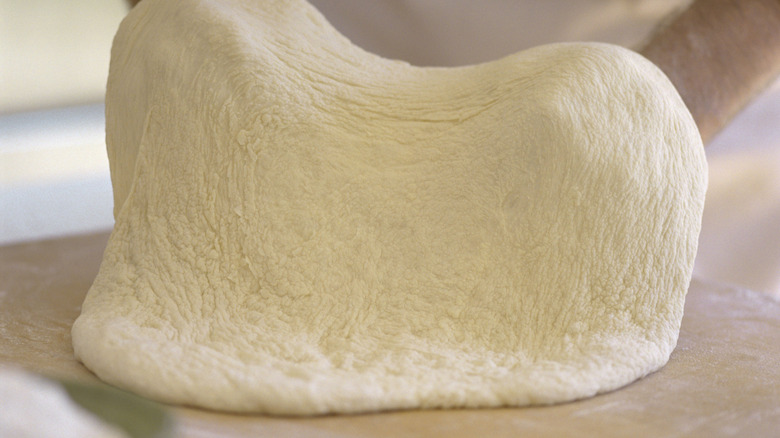 Person stretching out pizza dough