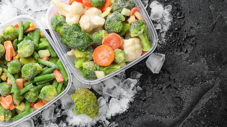 Packs of frozen vegetables are sitting on ice.