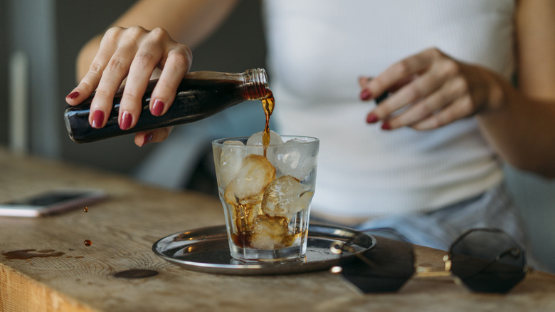 A woman pours cold brew into a cup