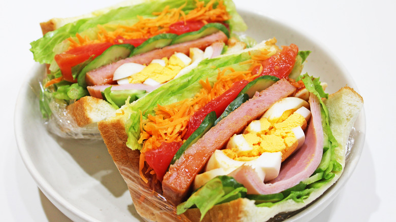 A Spam sandwich with lettuce, egg, tomato, cheese, and cucumber