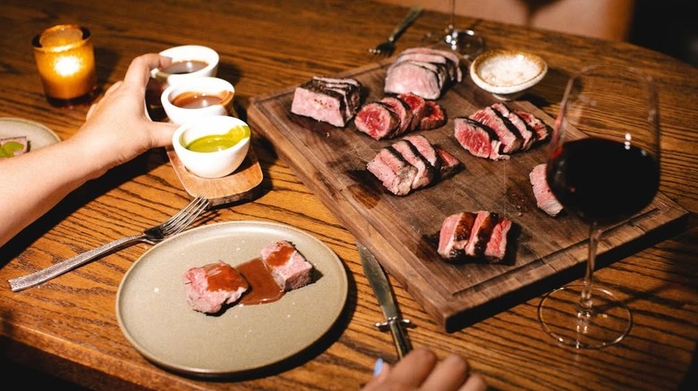 Different slices of steak with sauces and wine