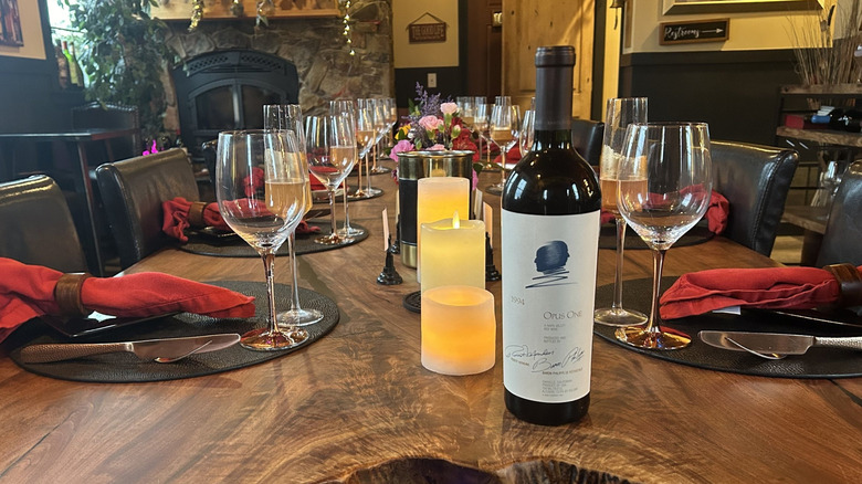 A long dining table set with wine glasses and a wine bottle