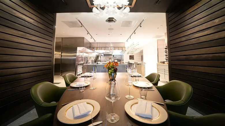 A dining table looks out of an alcove at a professional kitchen
