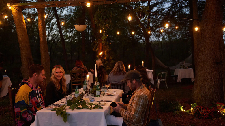 People dining outdoors under lights