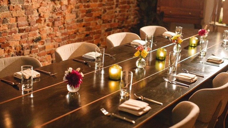 An elegant communal dining table in a brick-walled dining room