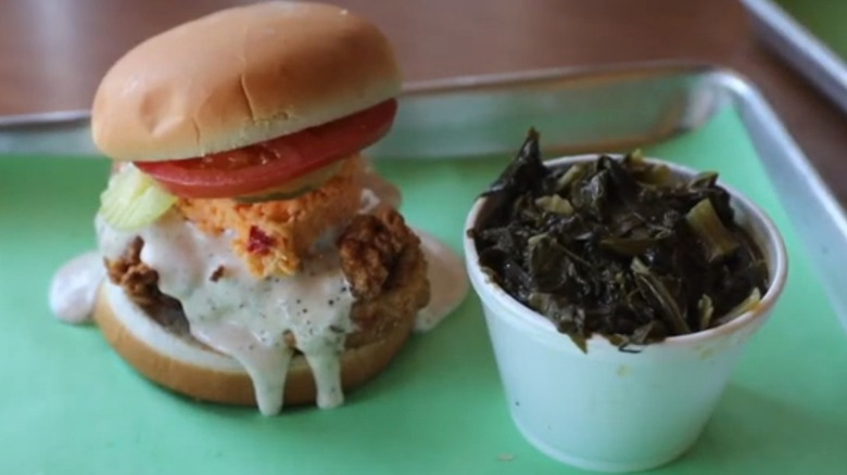 Chicken sandwich with white sauce and a bowl of collard greens from Saw's BBQ