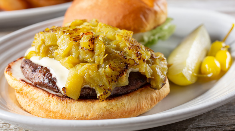 Open green chile cheeseburger on a white plate