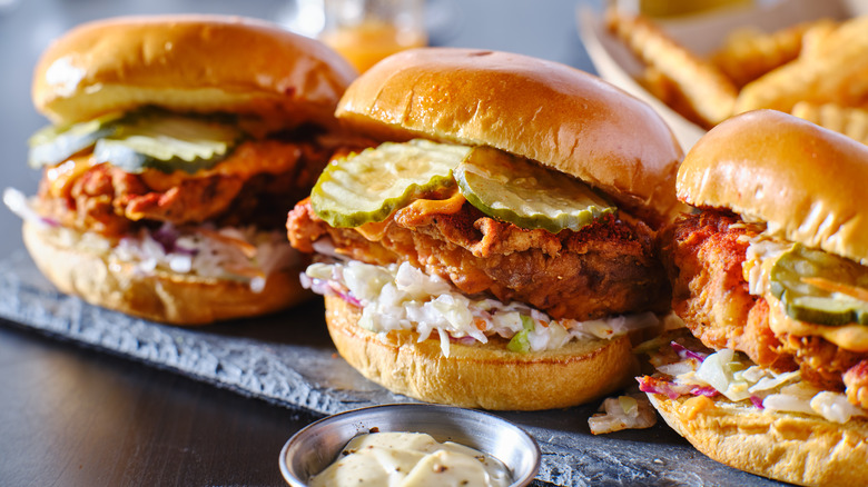 Three Nashville hot chicken sandwiches with slaw and pickles