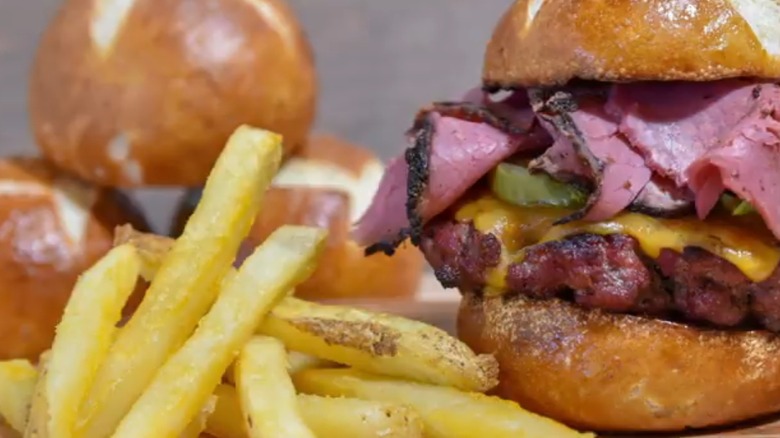 Pastrami burger on a pretzel bun with fries