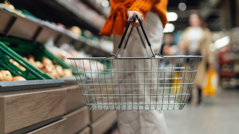 Hand holding shopping basket at grocery store