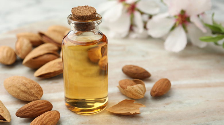 Almonds scattered next to a bottle of almond extract.