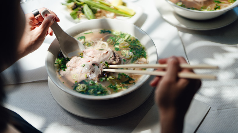 Bowl of pho eaten with spoon and chopsticks