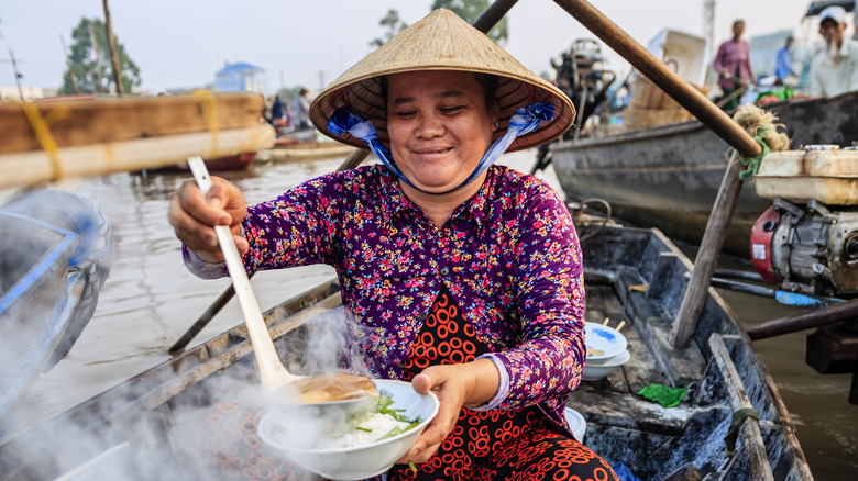 A Vietnamese woman serving pho