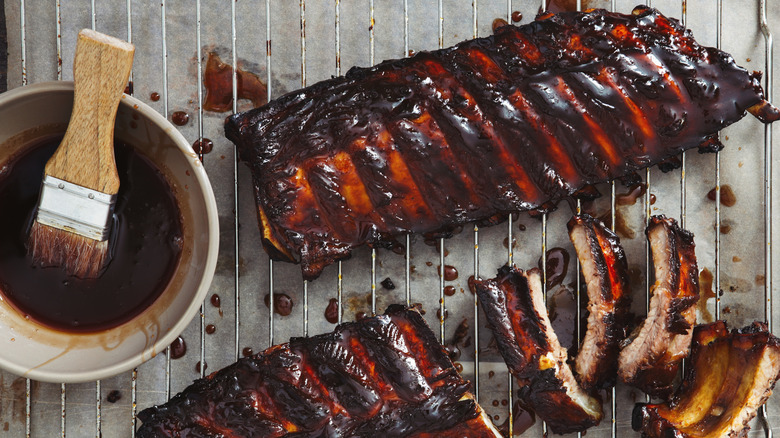 Barbecue ribs on a grate with bowl of sauce