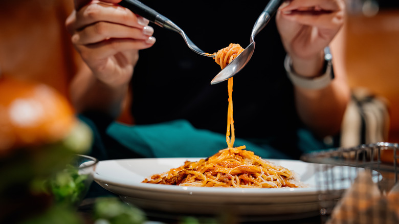 A person spooling up a forkful of spaghetti