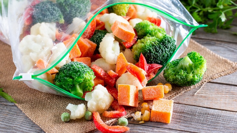 Frozen vegetables spilling out of a freezer bag.