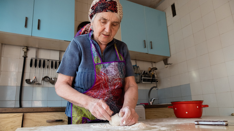 A senior woman kneading dough