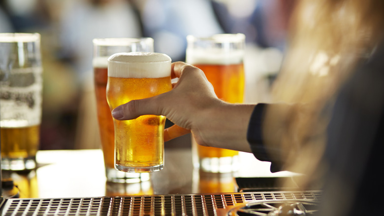 Bartender serving frothy beers in cold glasses