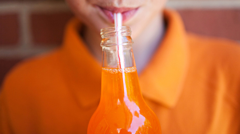 Boy drinking orange soda from straw