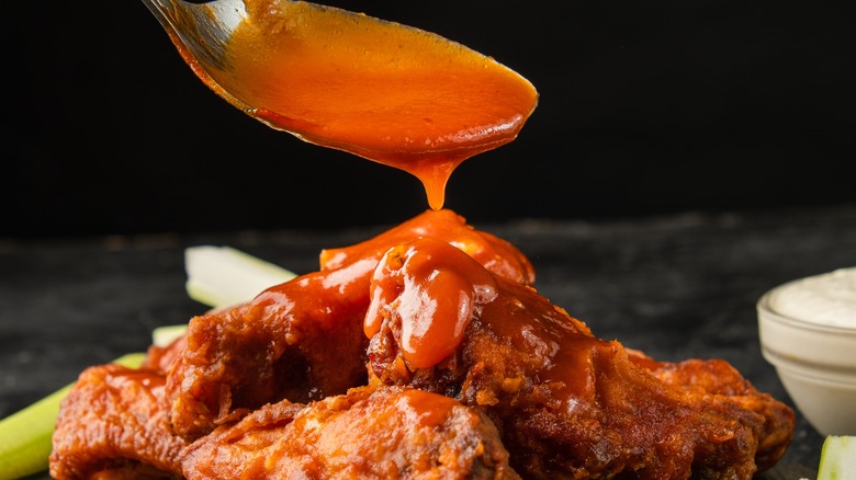 Spoon Pouring Buffalo Sauce on Wings